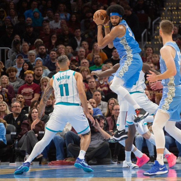 Cleveland Cavaliers' Jarrett Allen, center, grabs a rebound as Charlotte Hornets' Cody Martin (11) and Dean Wade, right, look on during the second half of an NBA basketball game in Cleveland, Sunday, Nov 17, 2024. (AP Photo/Phil Long)