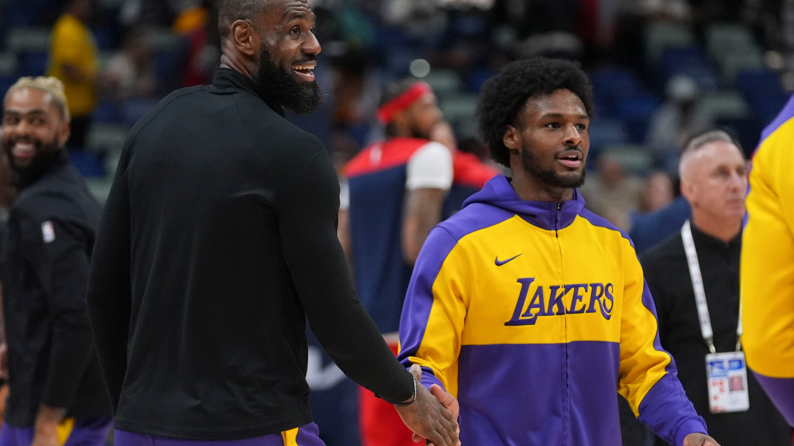 Los Angeles Lakers forward LeBron James greets his son guard Bronny James, right during warm-ups before an NBA basketball game against the New Orleans Pelicans in New Orleans, Saturday, Nov. 16, 2024. (AP Photo/Gerald Herbert)