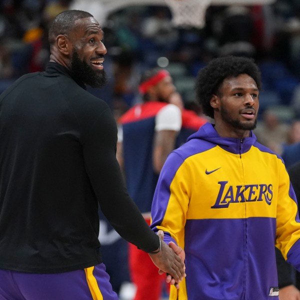 Los Angeles Lakers forward LeBron James greets his son guard Bronny James, right during warm-ups before an NBA basketball game against the New Orleans Pelicans in New Orleans, Saturday, Nov. 16, 2024. (AP Photo/Gerald Herbert)