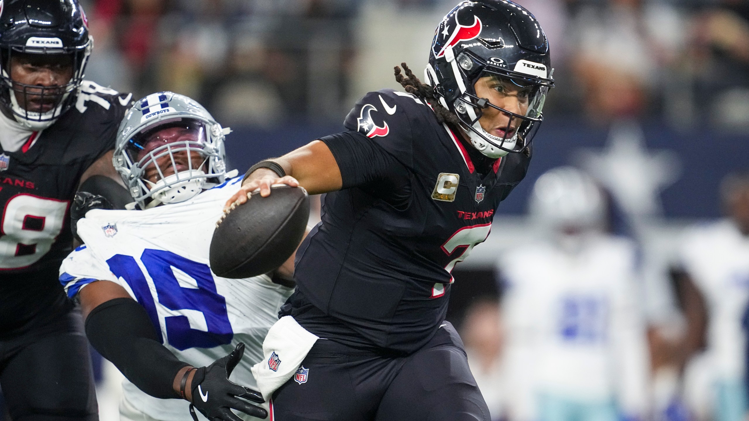 Houston Texans quarterback C.J. Stroud, right, gets help from offensive tackle Laremy Tunsil, left, to escape a tackle attempt by Dallas Cowboys quarterback Trey Lance during the second half of an NFL football game, Monday, Nov. 18, 2024, in Arlington, Texas. (AP Photo/Tony Gutierrez)