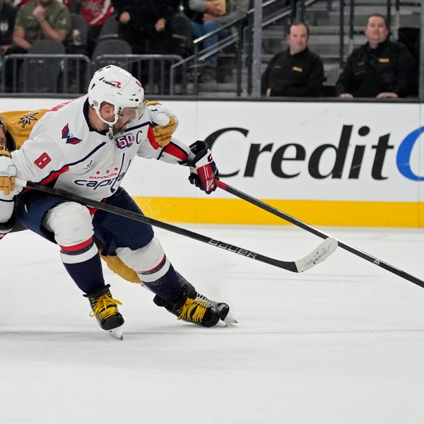 Washington Capitals left wing Alex Ovechkin (8) scores an open net goal past Vegas Golden Knights defenseman Shea Theodore (27) for a hat trick during the third period of an NHL hockey game Sunday, Nov. 17, 2024, in Las Vegas. (AP Photo/John Locher)