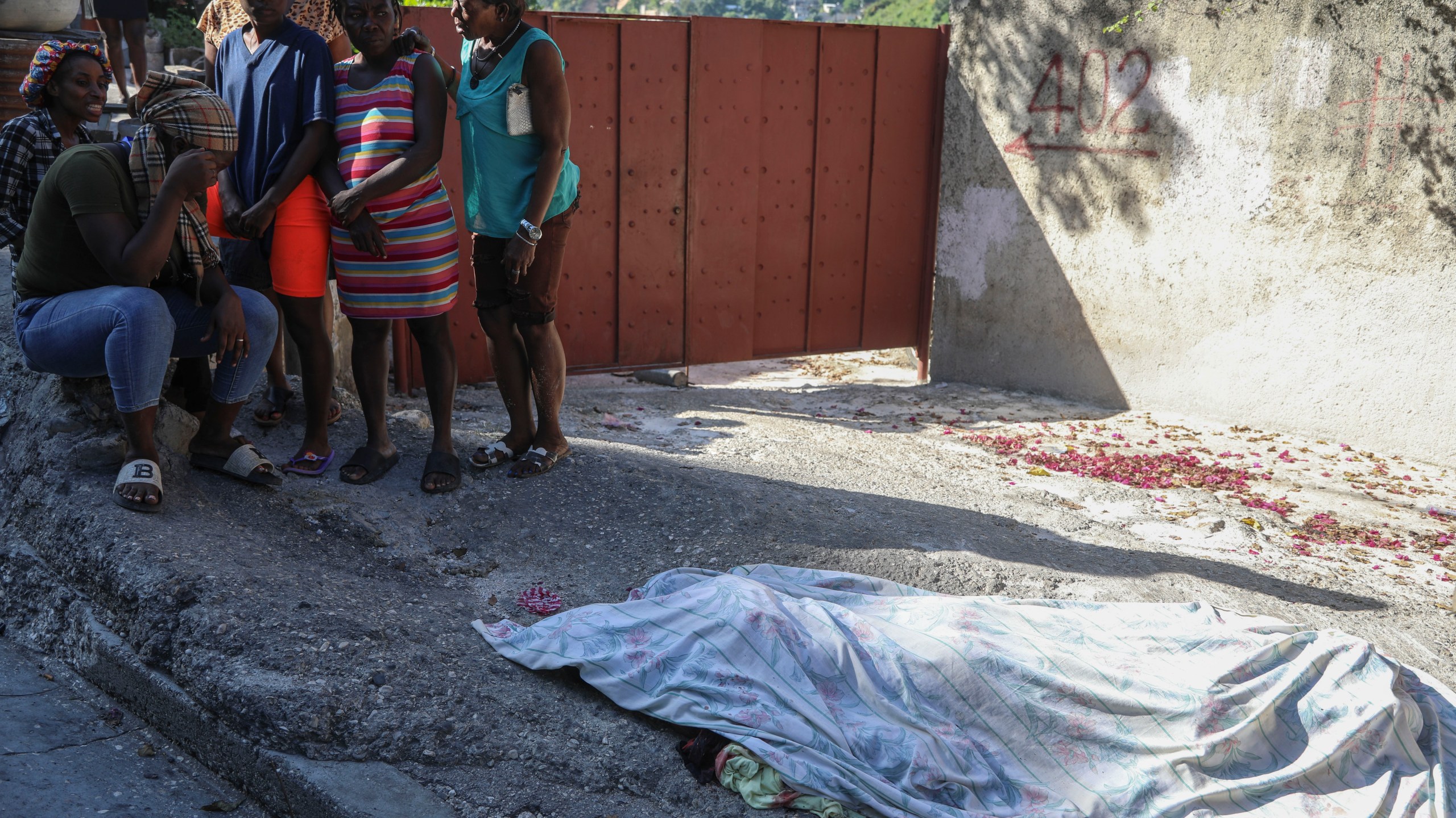 Residents gather before a person they say was killed in an attack by gang members, in the Pétion-Ville neighborhood of Port-au-Prince, Haiti, Tuesday, Nov. 19, 2024. (AP Photo/Odelyn Joseph)