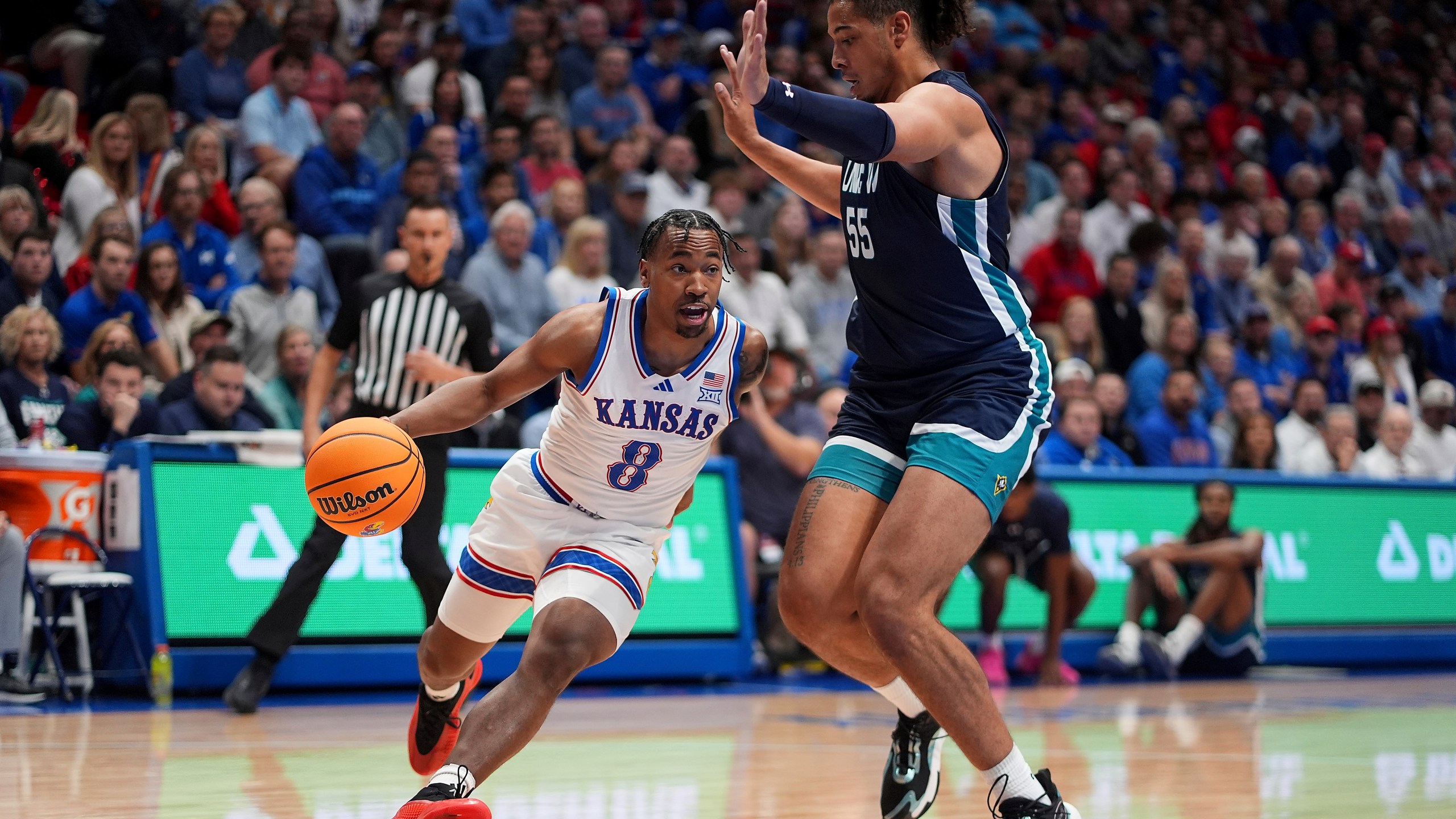 Kansas guard David Coit (8) drives past UNC Wilmington forward Harlan Obioha (55) during the first half of an NCAA college basketball game Tuesday, Nov. 19, 2024, in Lawrence, Kan. (AP Photo/Charlie Riedel)