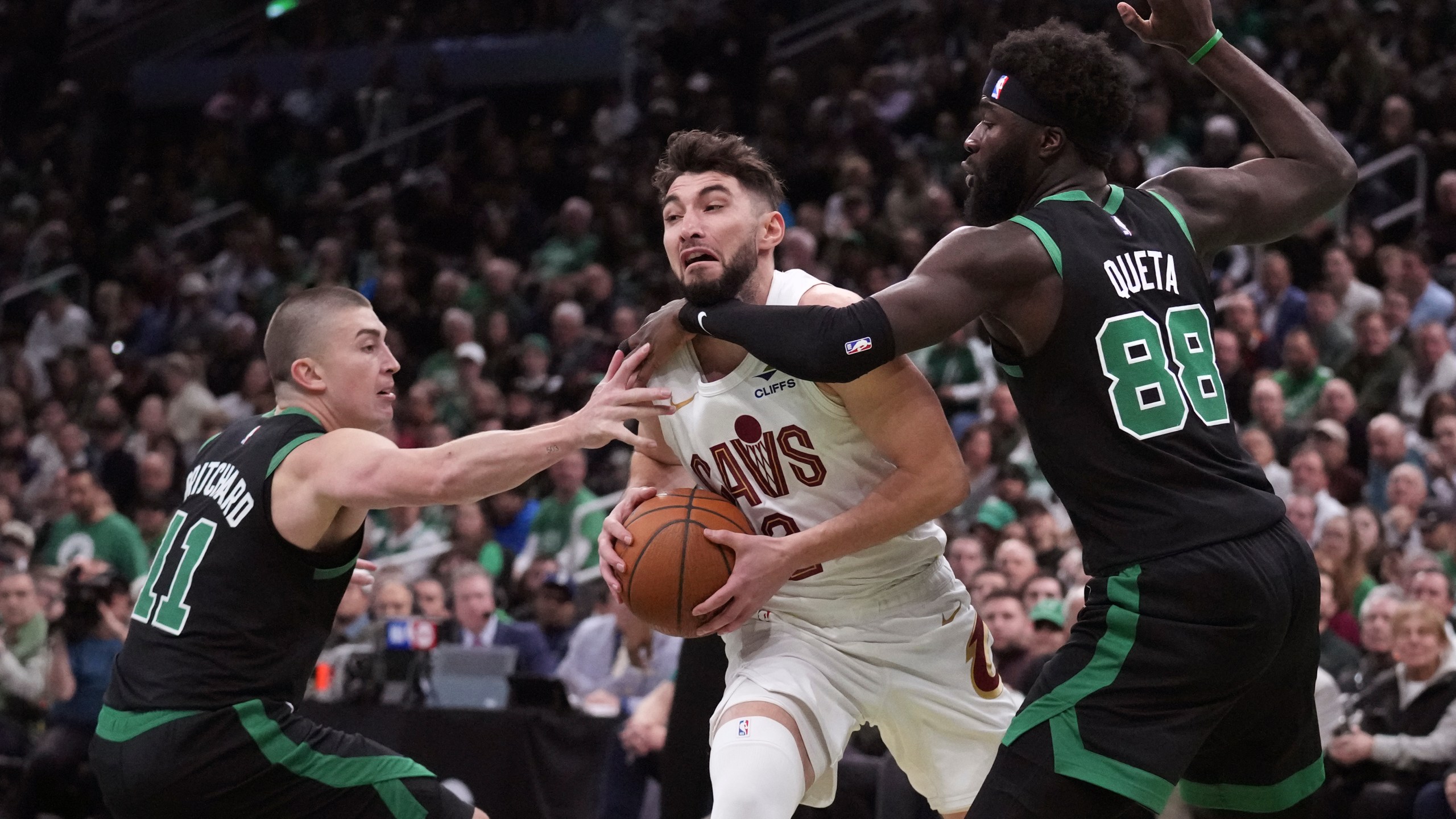 Cleveland Cavaliers guard Ty Jerome, center, tries to drive between Boston Celtics guard Payton Pritchard (11) and center Neemias Queta (88) during the first half of an Emirates NBA Cup basketball game, Tuesday, Nov. 19, 2024, in Boston. (AP Photo/Charles Krupa)