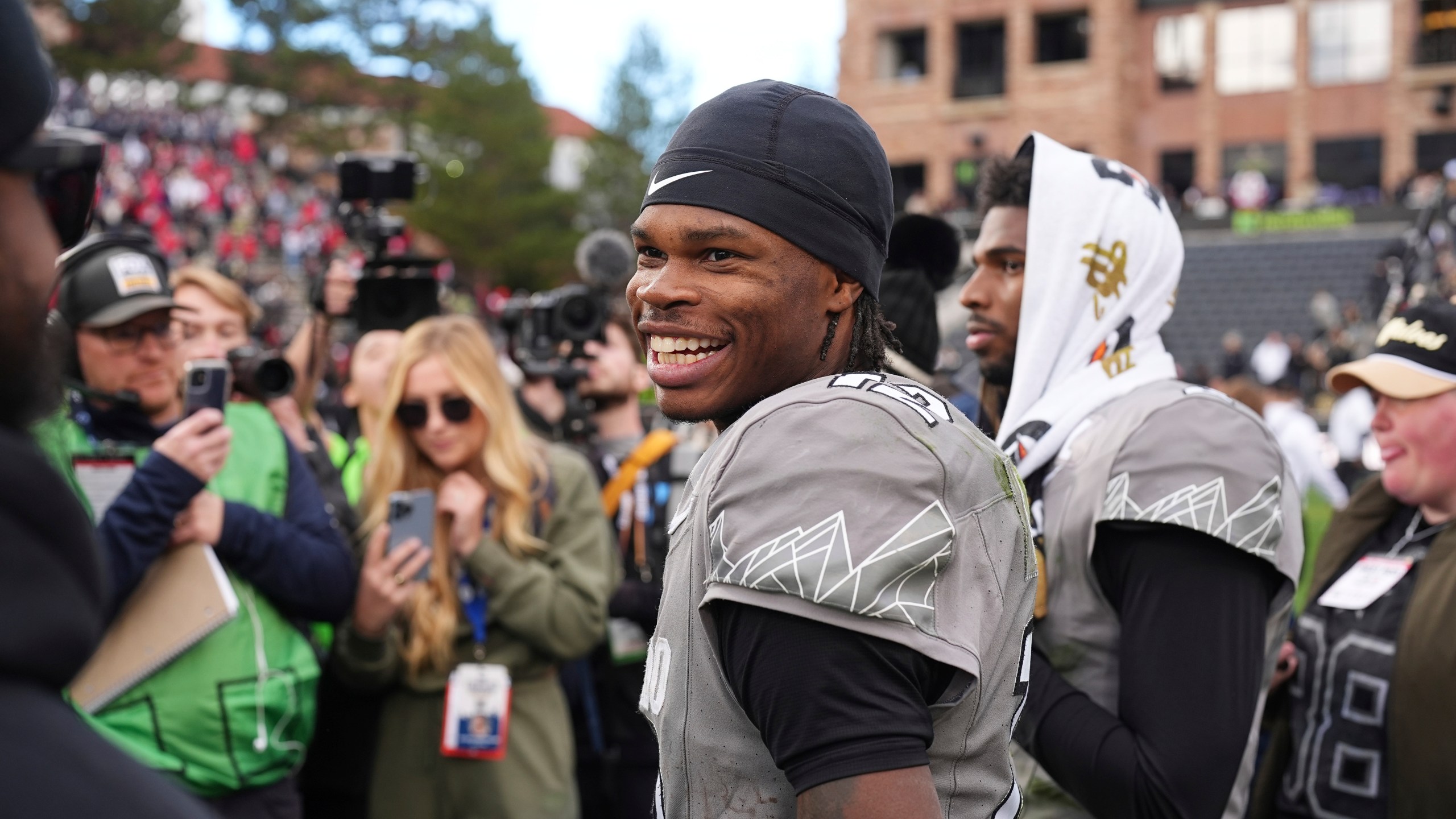 Colorado wide receiver Travis Hunter, front, jokes with teammates as he waits with quarterback Shedeur Sanders to do a television interview after an NCAA college football game against Utah Saturday, Nov. 16, 2024, in Boulder, Colo. (AP Photo/David Zalubowski)