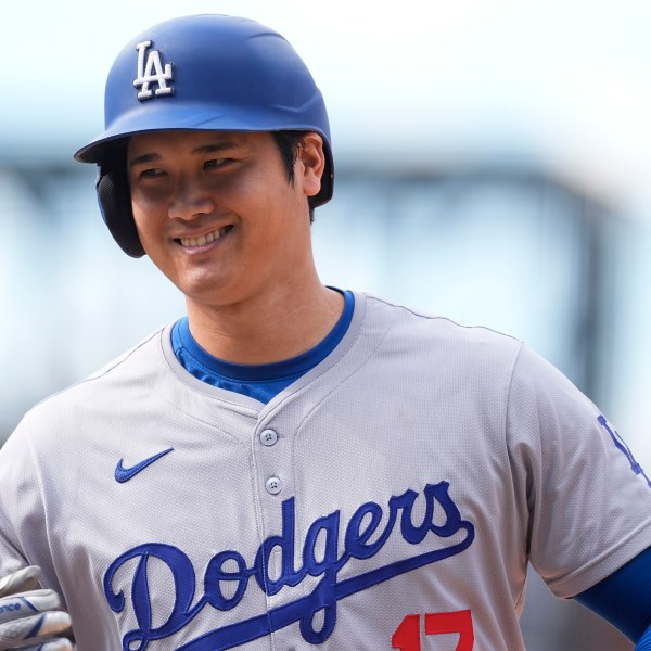 FILE - Los Angeles Dodgers' Shohei Ohtani smiles after reaching first base on a single off Colorado Rockies relief pitcher Seth Halvorsen in the eighth inning of a baseball game Sept. 29, 2024, in Denver. (AP Photo/David Zalubowski, File)