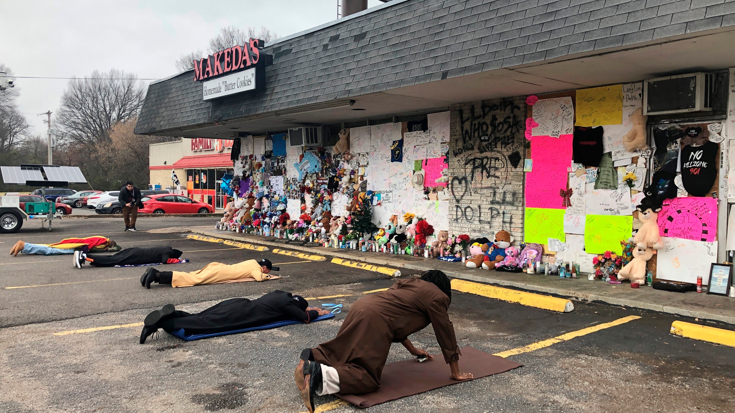 FILE - Mourners lie on the ground and pray in front of a memorial to slain rapper Young Dolph at Makeda's Homemade Cookies on Wednesday, Dec. 15, 2021, in Memphis, Tenn. (AP Photo/Adrian Sainz, File)