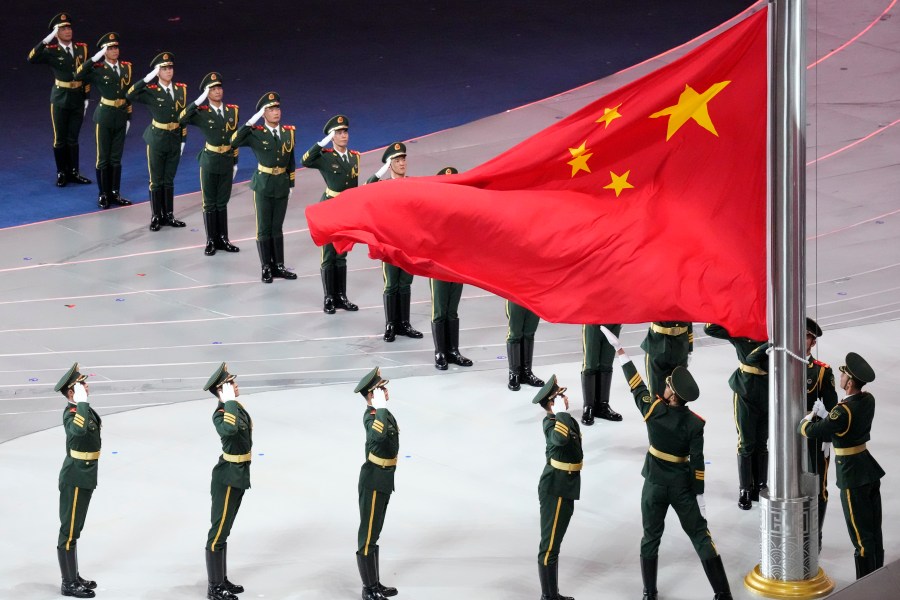 FILE - Military salute at the Chinese flag during the opening ceremony of the 19th Asian Games in Hangzhou, China, on Sept. 23, 2023. (AP Photo/Eugene Hoshiko, File)