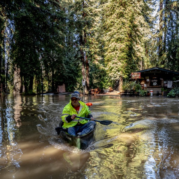 John Phillips, front, and neighbor Kevin Ozorkiewicz row a canoe at the flooded Mirabel RV Park & Campground after a major storm in Forestville, Calif., Saturday, Nov. 23, 2024. (Stephen Lam/San Francisco Chronicle via AP)