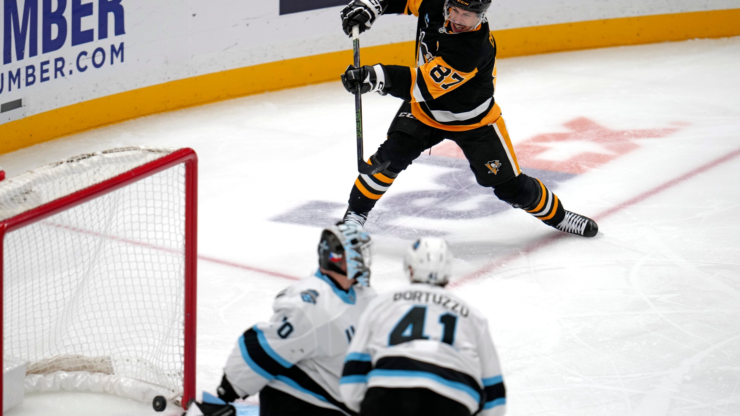 Pittsburgh Penguins' Sidney Crosby (87) gets a shot behind Utah Hockey Club goaltender Karel Vejmelka (70) for his 600th career goal in the NHL during the second period of an NHL hockey game Saturday, Nov. 23, 2024, in Pittsburgh. (AP Photo/Gene J. Puskar)