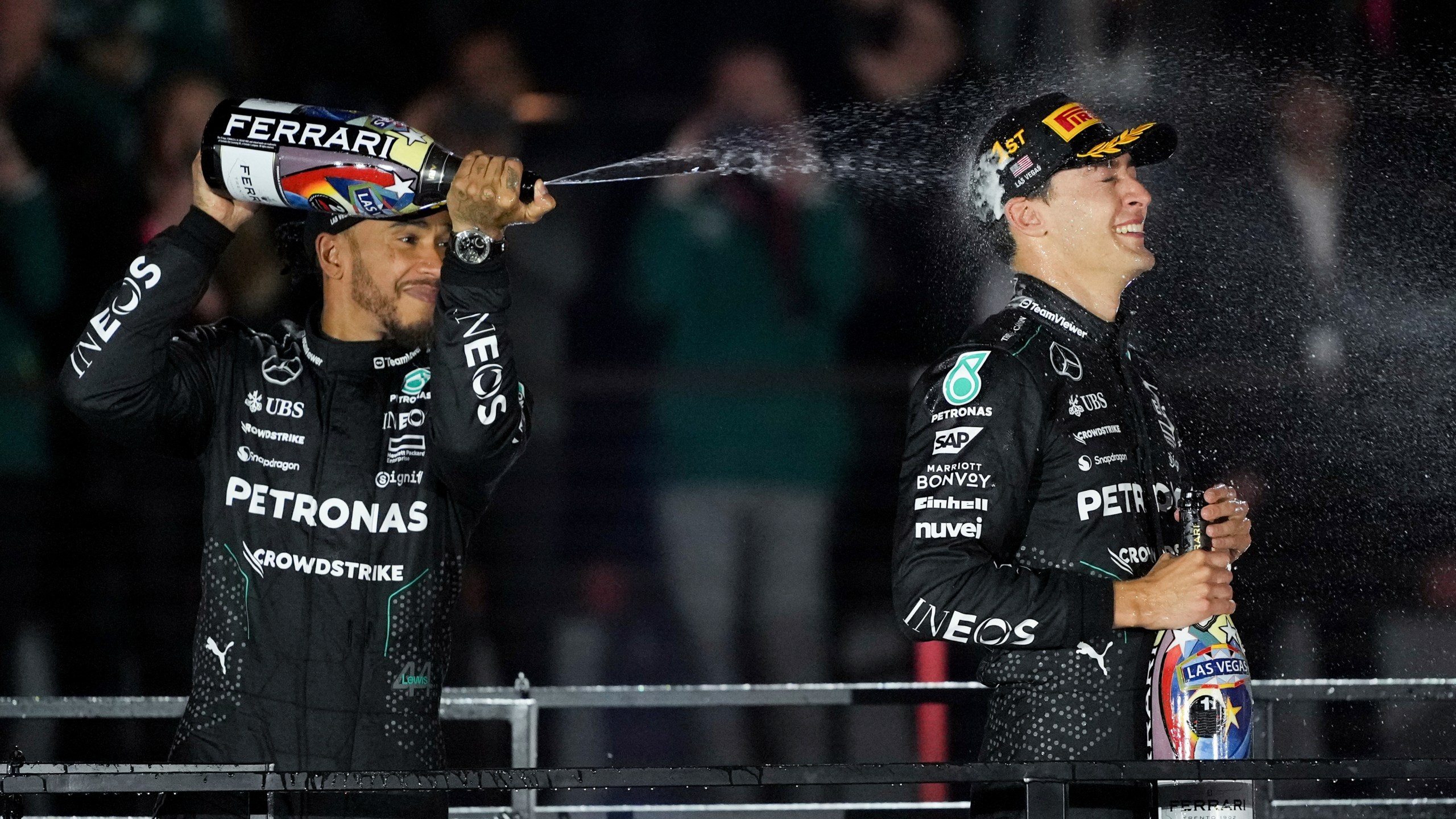 Mercedes driver Lewis Hamilton, of Britain, left, sprays champagne on race winner Mercedes driver George Russell, of Britain, after the F1 Las Vegas Grand Prix auto race, Saturday, Nov. 23, 2024, in Las Vegas. (AP Photo/Rick Scuteri)