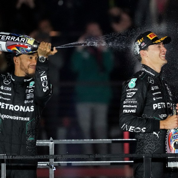 Mercedes driver Lewis Hamilton, of Britain, left, sprays champagne on race winner Mercedes driver George Russell, of Britain, after the F1 Las Vegas Grand Prix auto race, Saturday, Nov. 23, 2024, in Las Vegas. (AP Photo/Rick Scuteri)