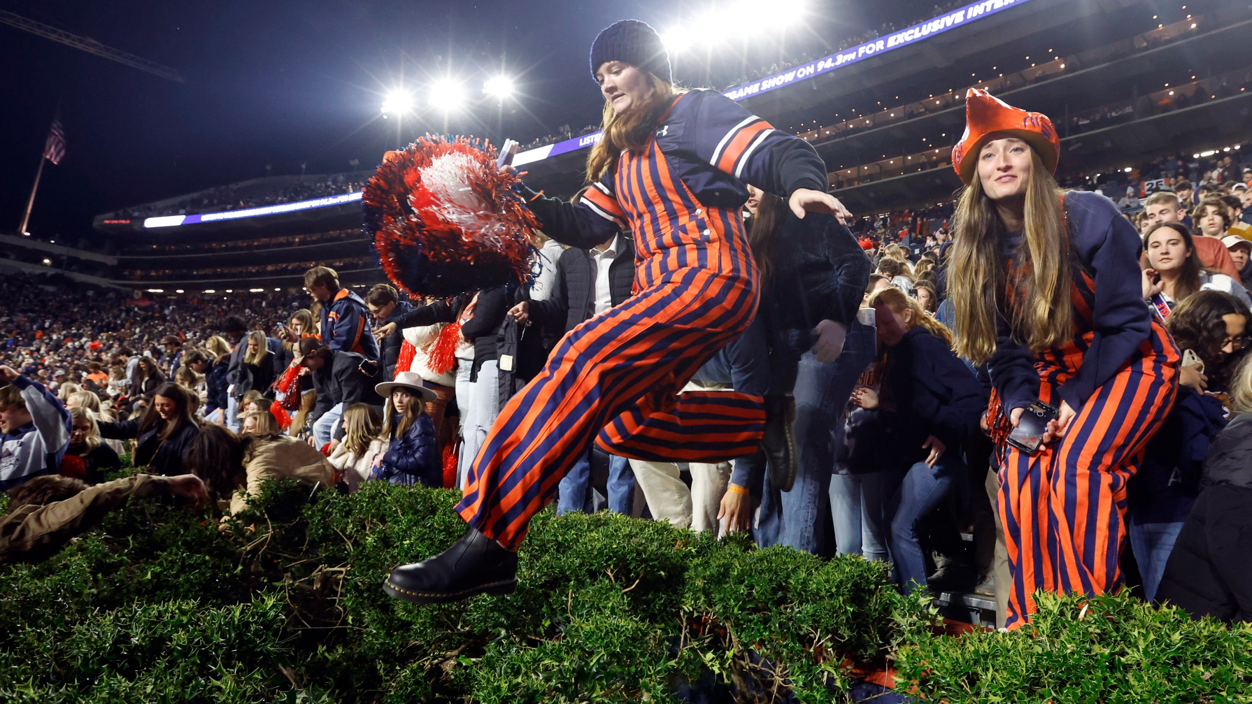 Auburn fans storm the field after defeating Texas A&M during the fourth overtime of an NCAA college football game, Saturday, Nov. 23, 2024, in Auburn, Ala. (AP Photo/Butch Dill)