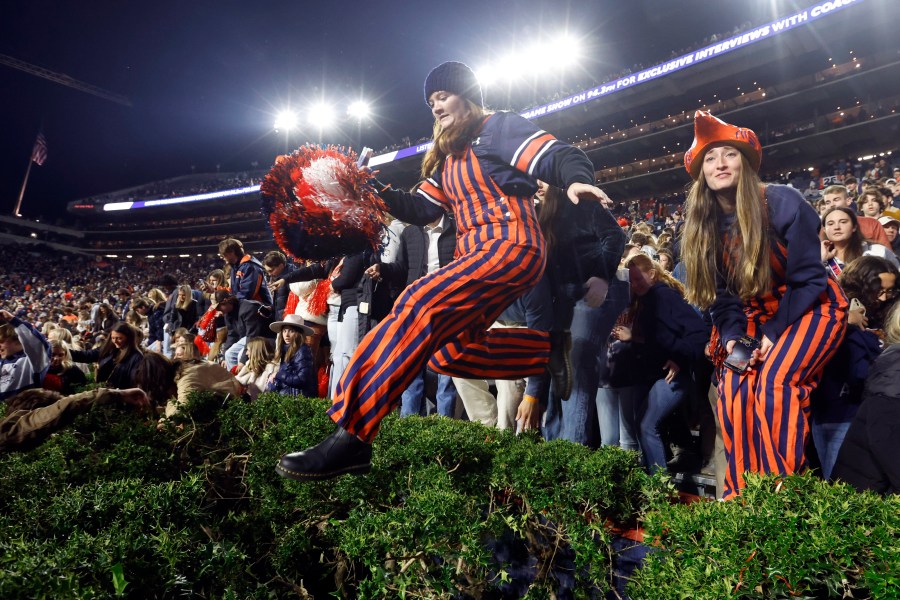 Auburn fans storm the field after defeating Texas A&M during the fourth overtime of an NCAA college football game, Saturday, Nov. 23, 2024, in Auburn, Ala. (AP Photo/Butch Dill)