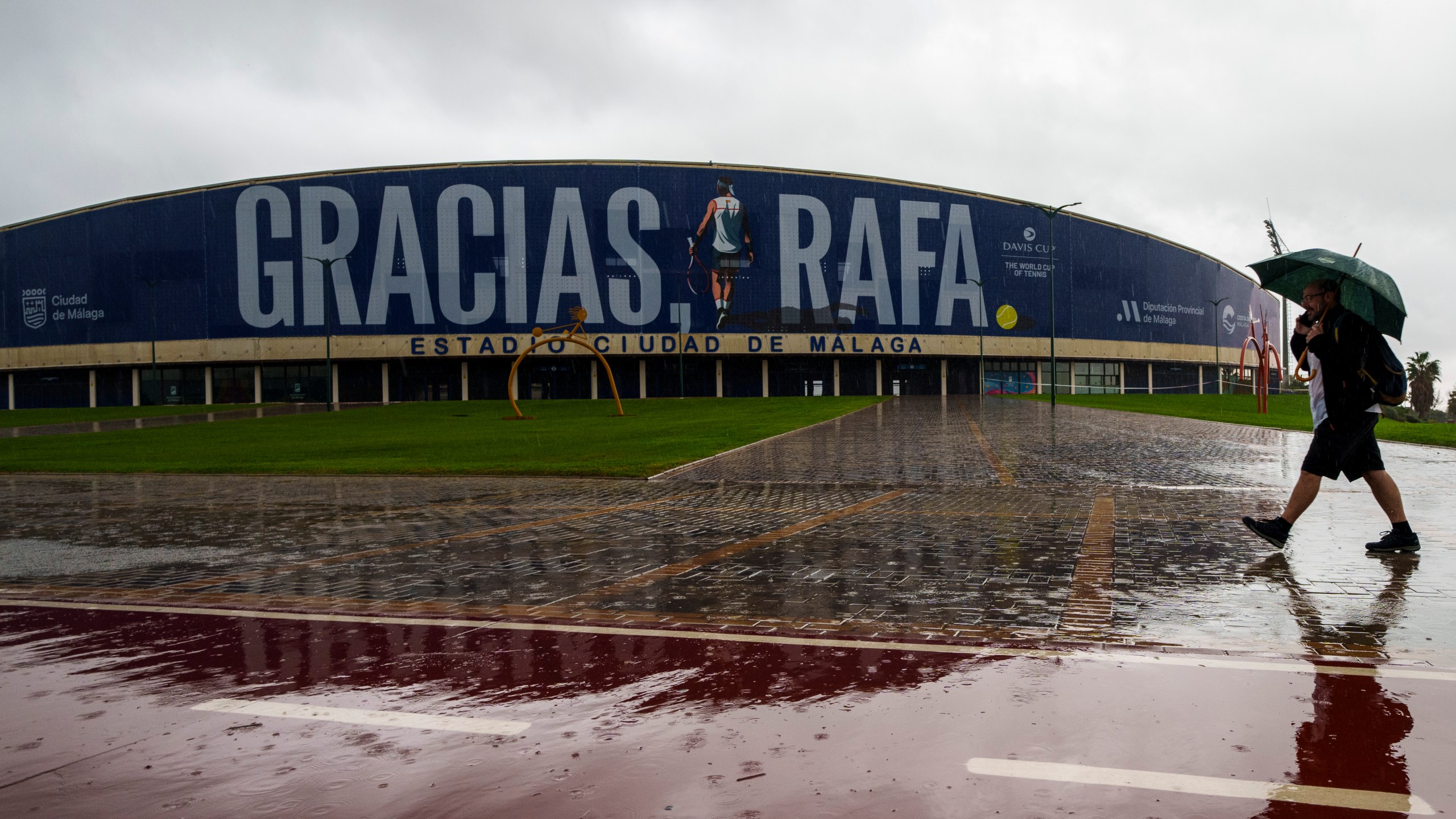 A man walks in front a banner reading in Spanish: "Thank you Rafa" during the Billie Jean King Cup finals at the Martin Carpena sportshall in Malaga, southern Spain, Wednesday, Nov. 13, 2024, after today's matches were canceled due to heavy rain and postponed until tomorrow. (AP Photo/Manu Fernandez)