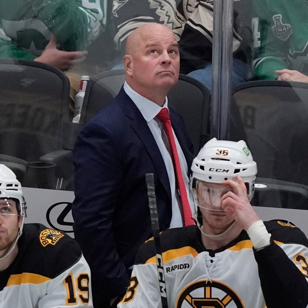 FILE - Boston Bruins head coach Jim Montgomery looks on from the bench with centers John Beecher (19) and Patrick Brown (38) during the first period of an NHL hockey game against the Dallas Stars, Nov. 14, 2024, in Dallas. (AP Photo/LM Otero, file)