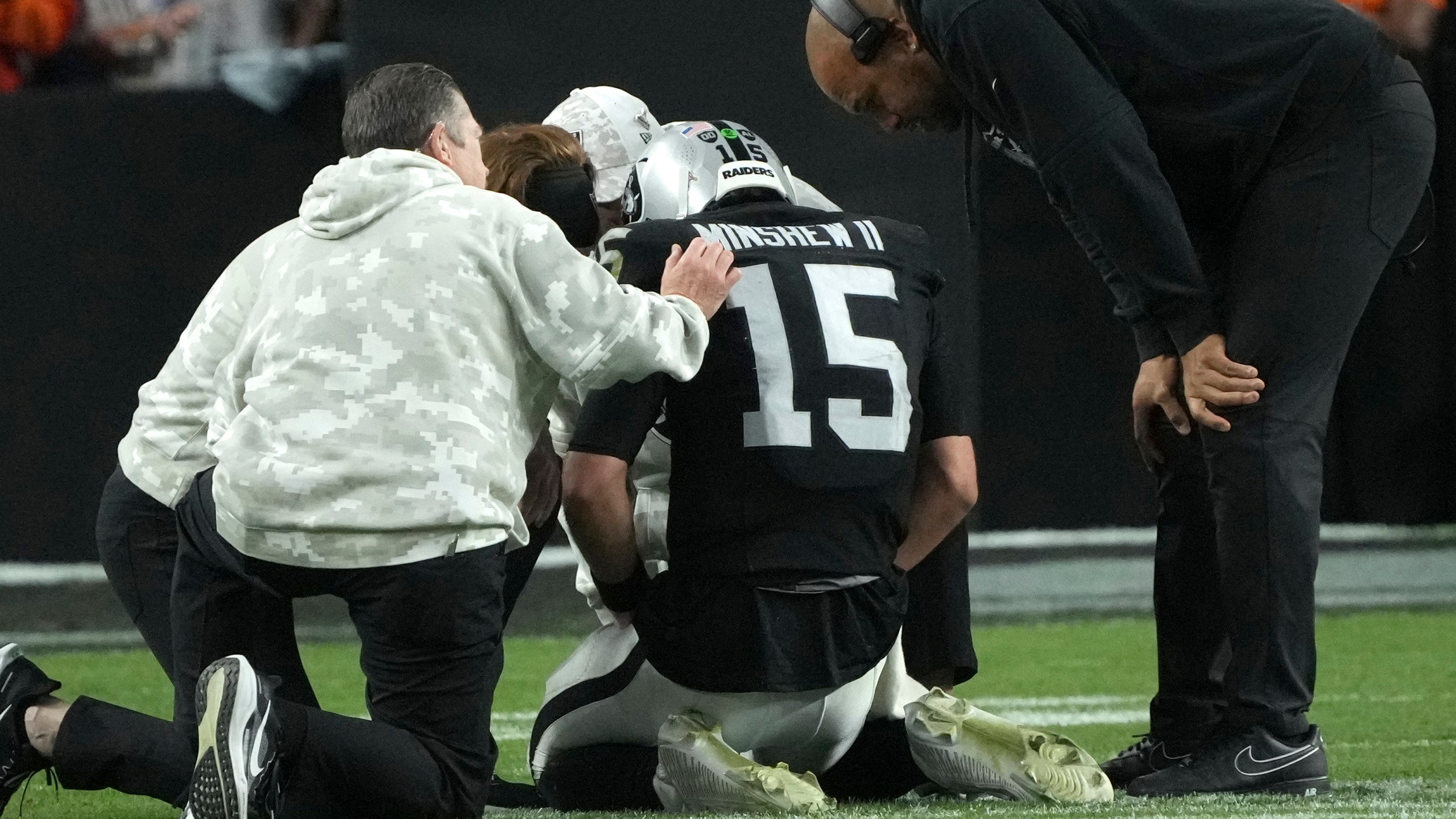 Las Vegas Raiders quarterback Gardner Minshew (15) is assisted by trainers and Head Coach Antonio Pierce, right, after an injury during the second half of an NFL football game against the Denver Broncos, Sunday, Nov. 24, 2024, in Las Vegas. (AP Photo/Rick Scuteri)