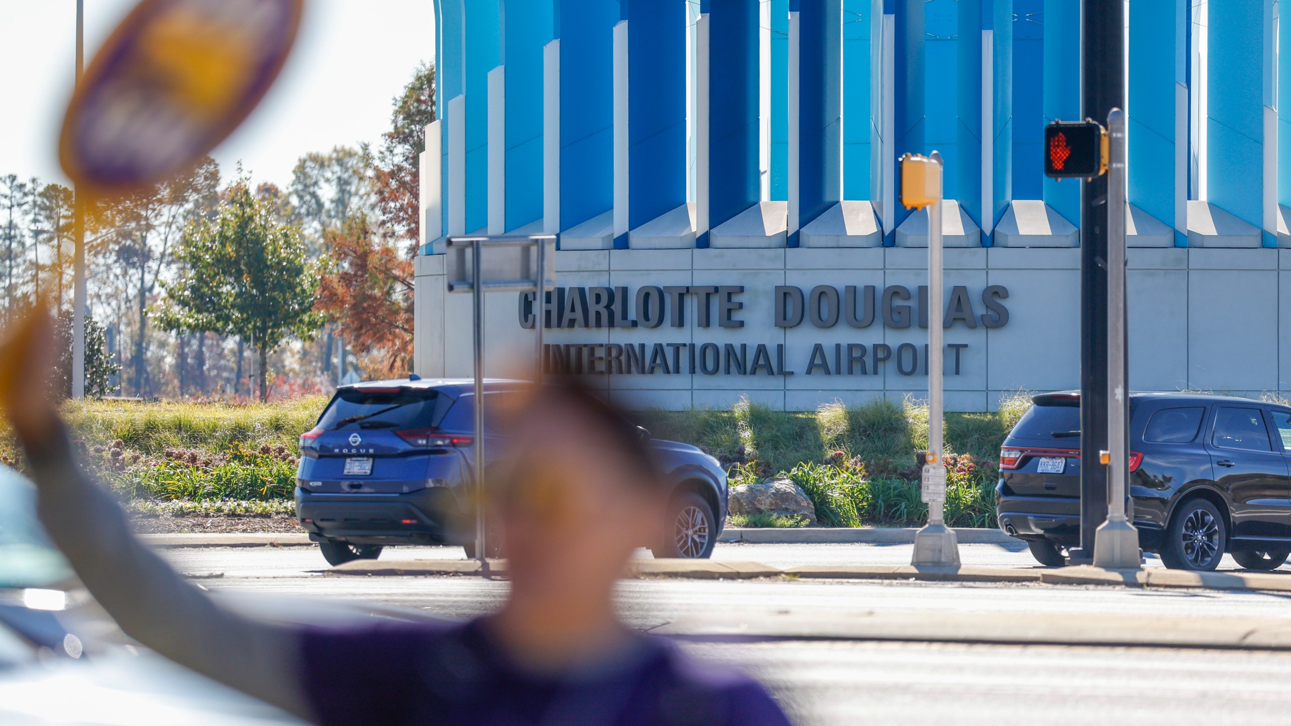 Airport workers wave signs as they march in front of the Charlotte Douglas International Airport in Charlotte, N.C., Monday, Nov. 25, 2024. (AP Photo/Nell Redmond)