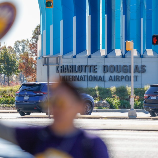 Airport workers wave signs as they march in front of the Charlotte Douglas International Airport in Charlotte, N.C., Monday, Nov. 25, 2024. (AP Photo/Nell Redmond)