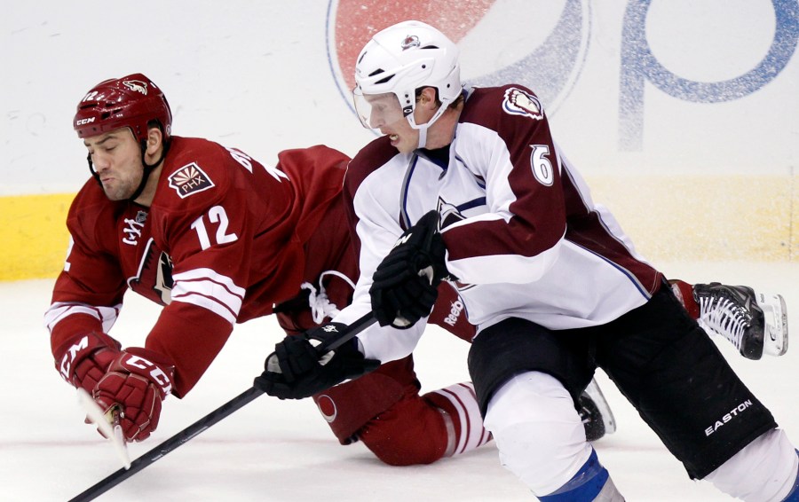 FILE - Phoenix Coyotes left winger Paul Bissonnette, left, and Colorado Avalanche defenseman Erik Johnson, right, compete for the puck in the third period of an NHL hockey game, April 6, 2013, in Glendale, Ariz. (AP Photo/Paul Connors, File)