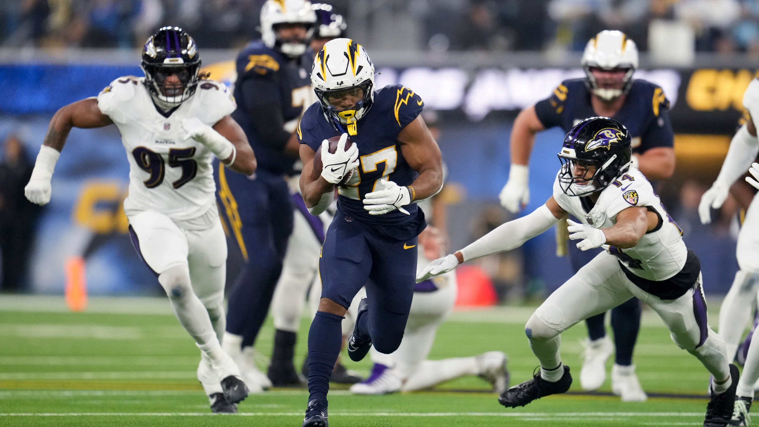 Los Angeles Chargers running back J.K. Dobbins (27) runs past Baltimore Ravens safety Kyle Hamilton (14) during the first half of an NFL football game Monday, Nov. 25, 2024, in Inglewood, Calif. (AP Photo/Eric Thayer)