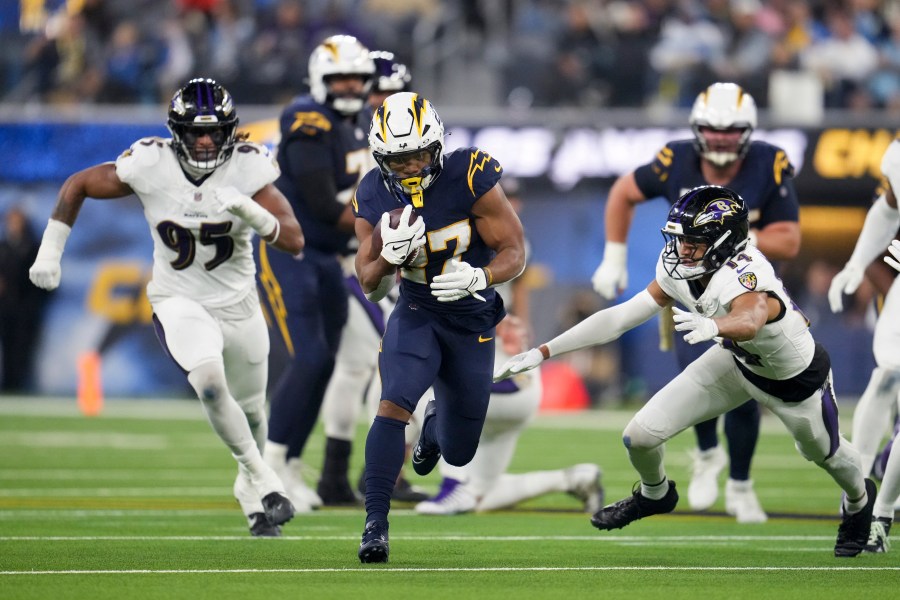 Los Angeles Chargers running back J.K. Dobbins (27) runs past Baltimore Ravens safety Kyle Hamilton (14) during the first half of an NFL football game Monday, Nov. 25, 2024, in Inglewood, Calif. (AP Photo/Eric Thayer)