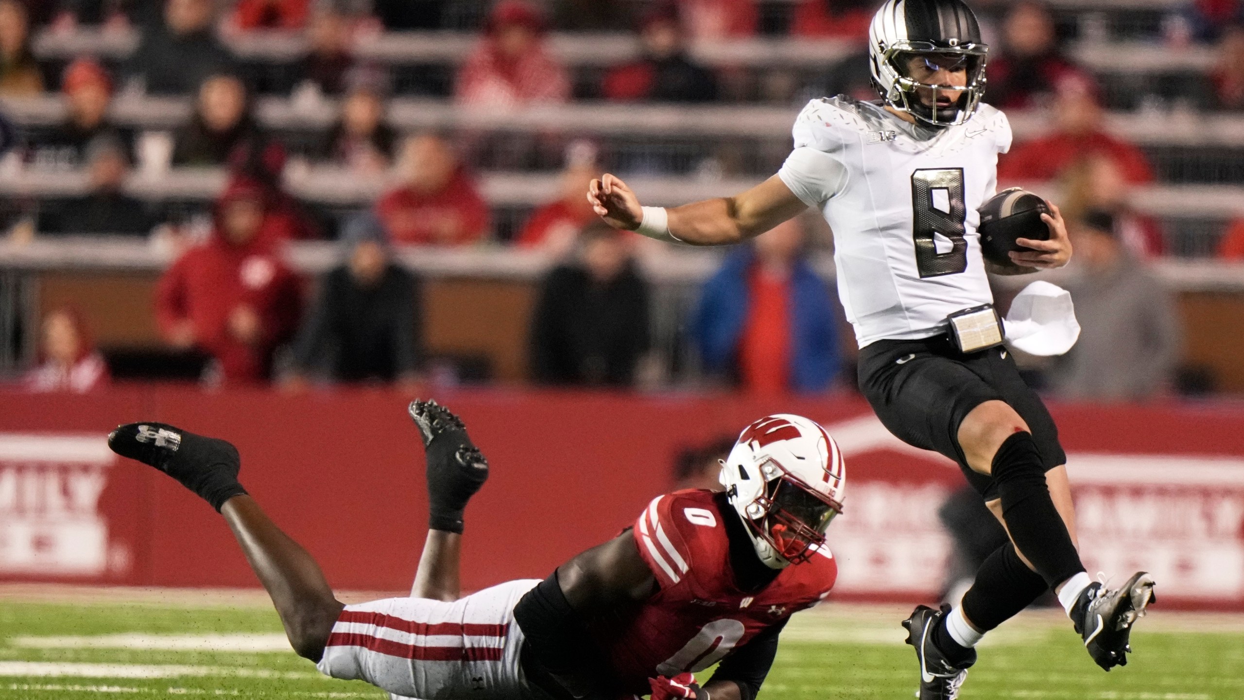 Oregon's Dillon Gabriel (8) runs past Wisconsin's John Pius (0) during the second half of an NCAA college football game Saturday, Nov. 16, 2024, in Madison, Wis. Oregon won 16-13. (AP Photo/Morry Gash)