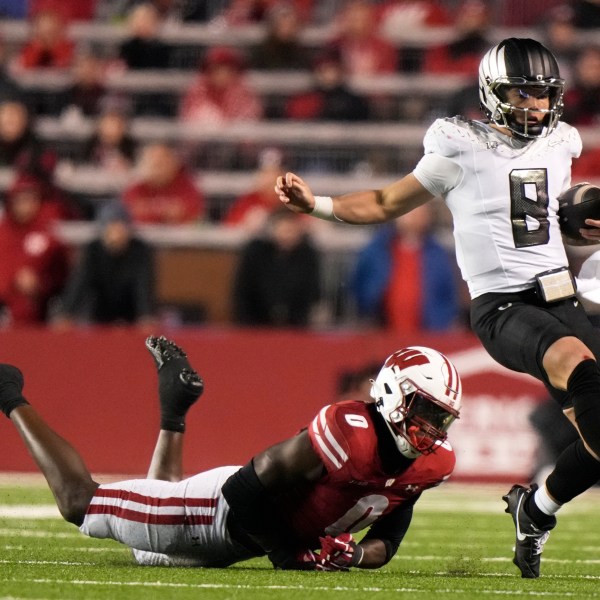 Oregon's Dillon Gabriel (8) runs past Wisconsin's John Pius (0) during the second half of an NCAA college football game Saturday, Nov. 16, 2024, in Madison, Wis. Oregon won 16-13. (AP Photo/Morry Gash)