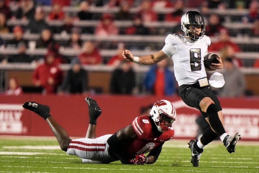 Oregon's Dillon Gabriel (8) runs past Wisconsin's John Pius (0) during the second half of an NCAA college football game Saturday, Nov. 16, 2024, in Madison, Wis. Oregon won 16-13. (AP Photo/Morry Gash)