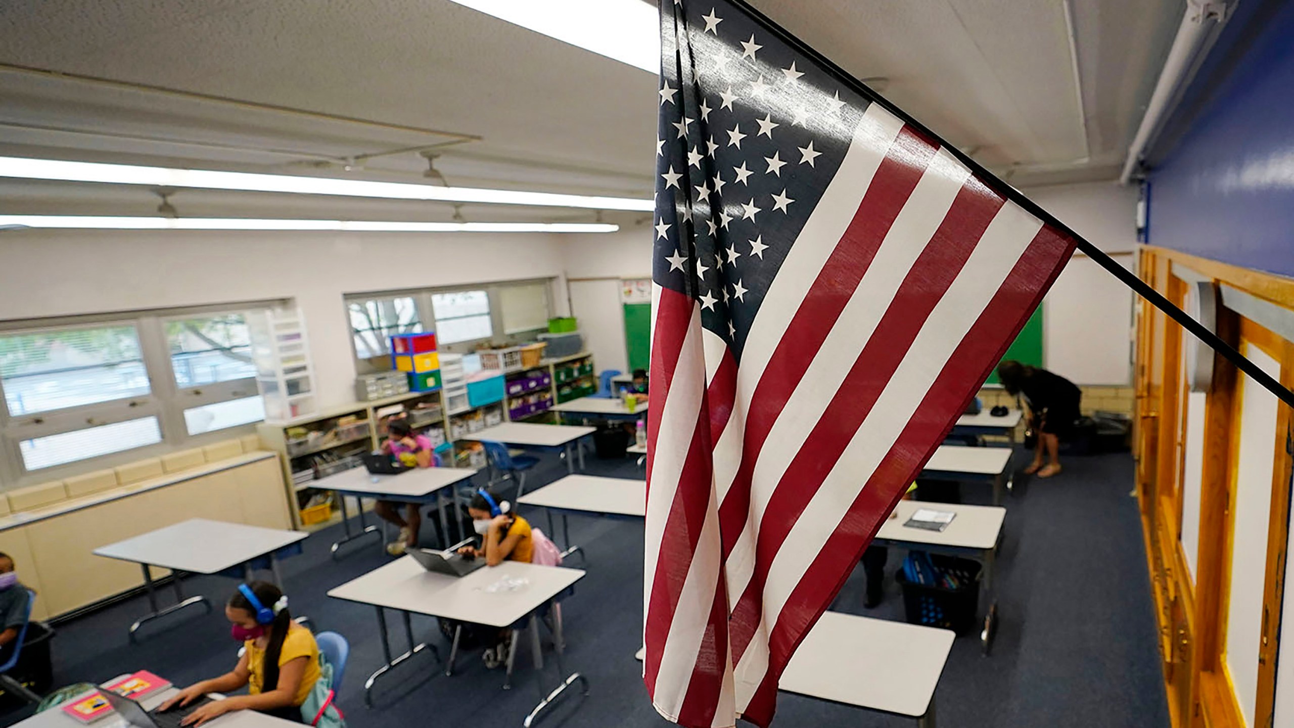 FILE - An American flag hangs in a classroom as students work on laptops in Newlon Elementary School, Aug. 25, 2020, in Denver. (AP Photo/David Zalubowski, File)