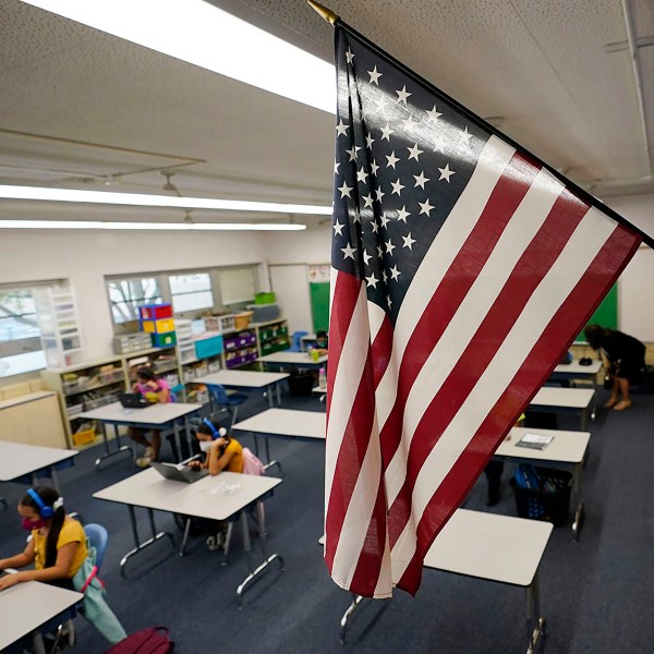 FILE - An American flag hangs in a classroom as students work on laptops in Newlon Elementary School, Aug. 25, 2020, in Denver. (AP Photo/David Zalubowski, File)