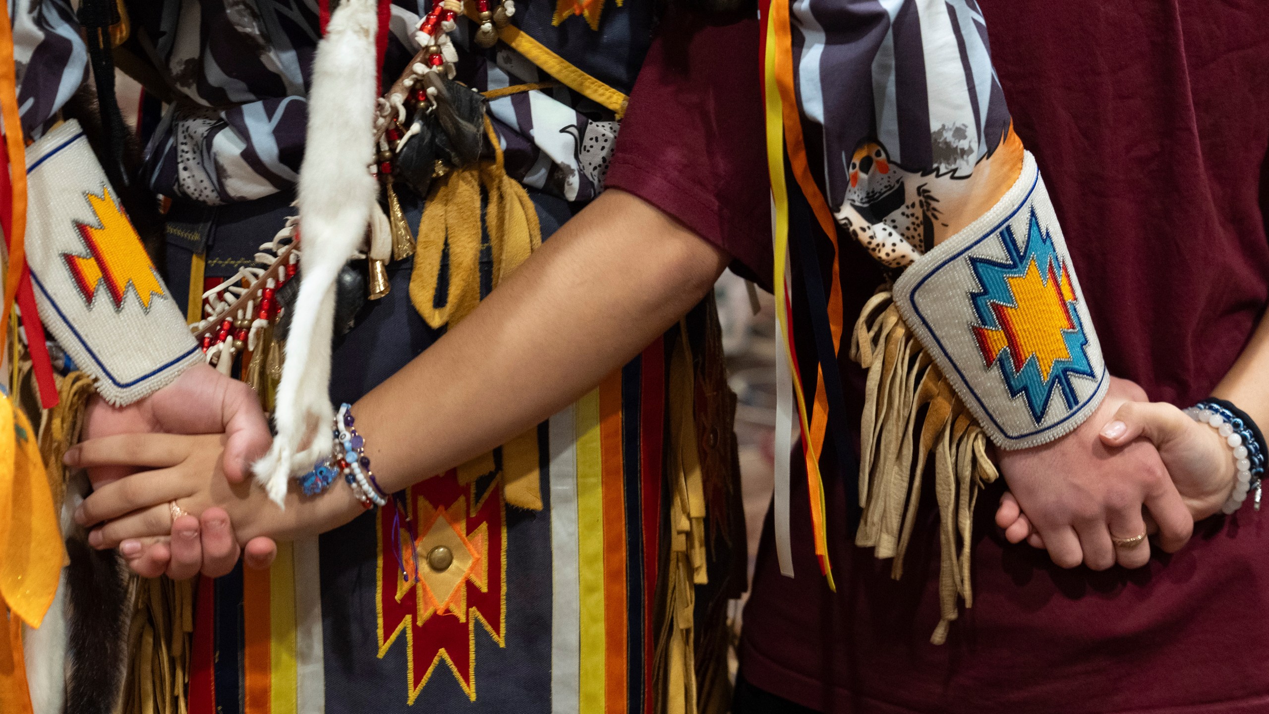 People hold hands during a dance at a powwow at Chinook Winds Casino Resort, Saturday, Nov. 16, 2024, in Lincoln City, Ore. (AP Photo/Jenny Kane)