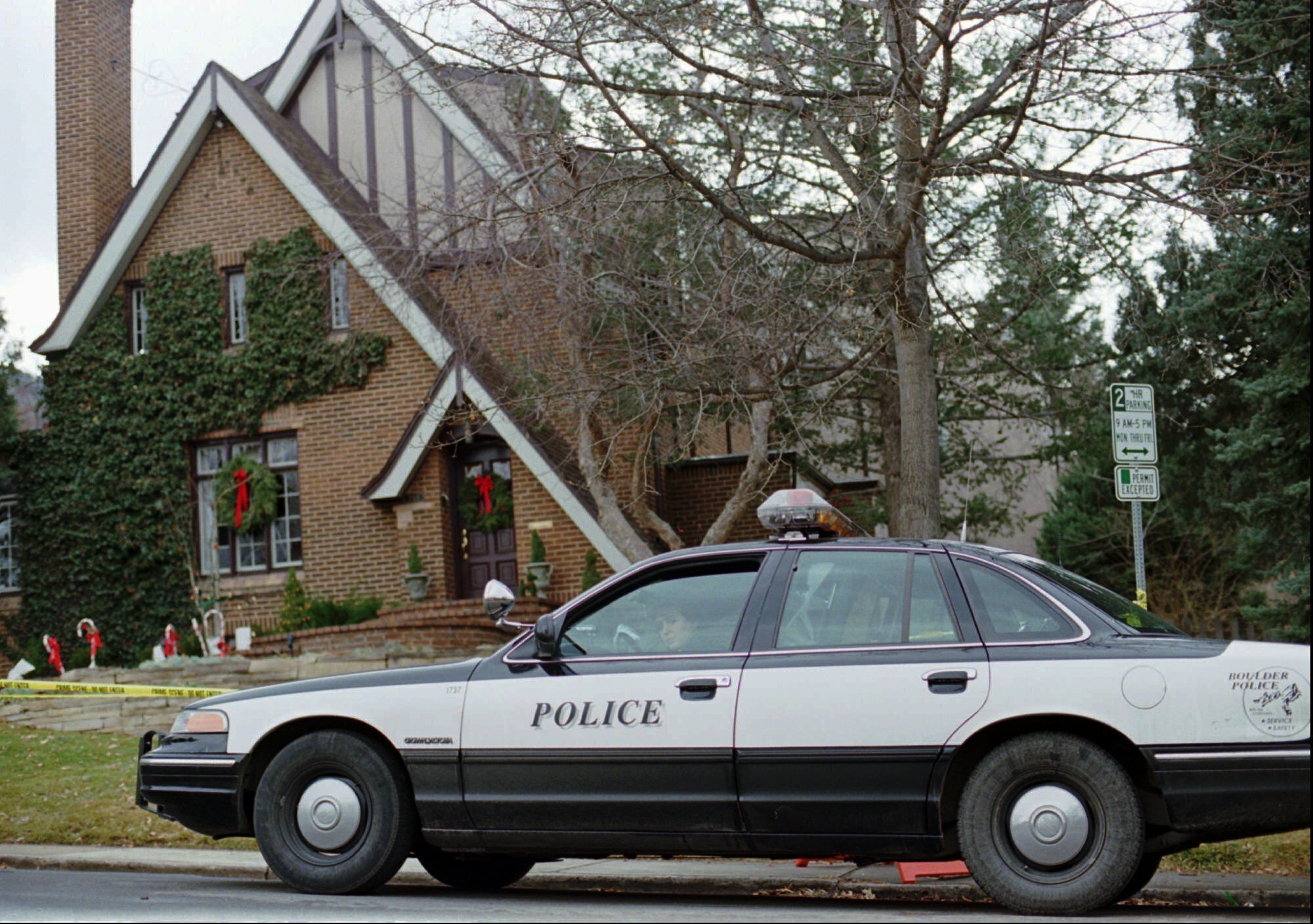 FILE - A police officer sits in her cruiser, Jan. 3, 1997, outside the home in which 6-year-old JonBenet Ramsey was found murdered in Boulder, Colo., on Dec. 26, 1996. (AP Photo/David Zalubowski, File)