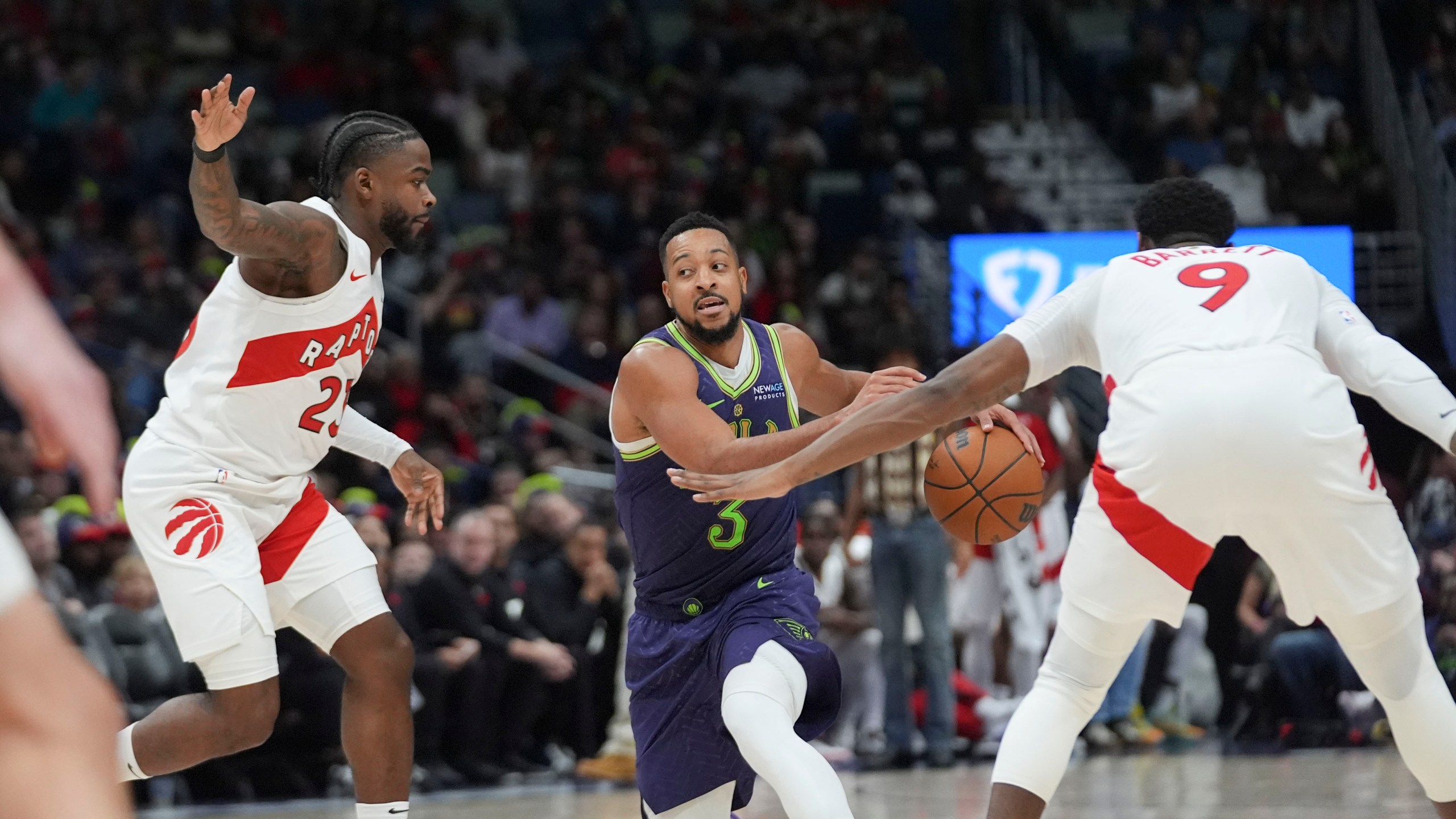 New Orleans Pelicans guard CJ McCollum (3) drives to the basket between Toronto Raptors guard Jamal Shead and guard RJ Barrett (9) in the second half of an NBA basketball game in New Orleans, Wednesday, Nov. 27, 2024. The Raptors won 119-93. (AP Photo/Gerald Herbert)