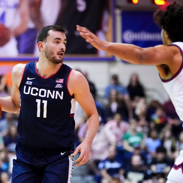 UConn forward Alex Karaban (11) looks to pass around Dayton forward Nate Santos (2) during the first half of an NCAA college basketball game at the Maui Invitational Wednesday, Nov. 27, 2024, in Lahaina, Hawaii. (AP Photo/Lindsey Wasson)