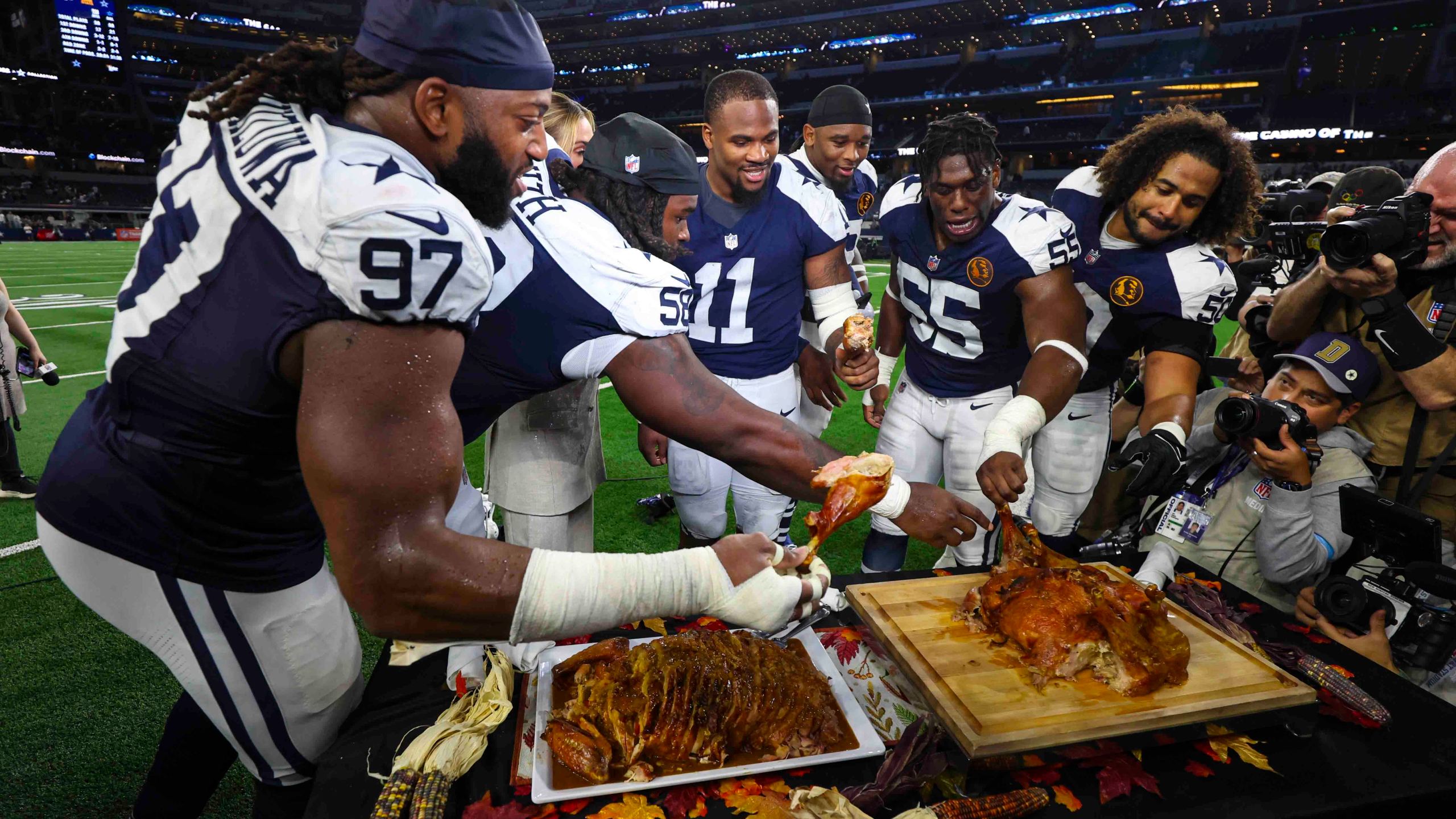 Dallas Cowboy players grab some turkey following an NFL football game against the New York Giants in Arlington, Texas, Thursday, Nov. 28, 2024. (AP Photo/Richard Roriguez)