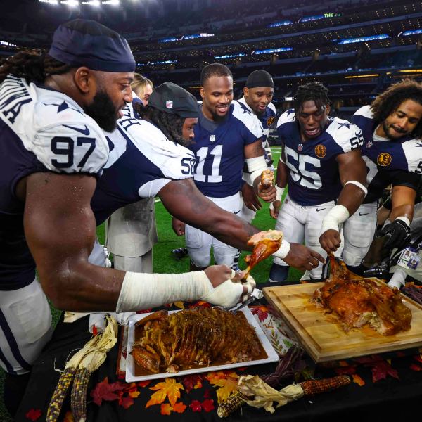 Dallas Cowboy players grab some turkey following an NFL football game against the New York Giants in Arlington, Texas, Thursday, Nov. 28, 2024. (AP Photo/Richard Roriguez)