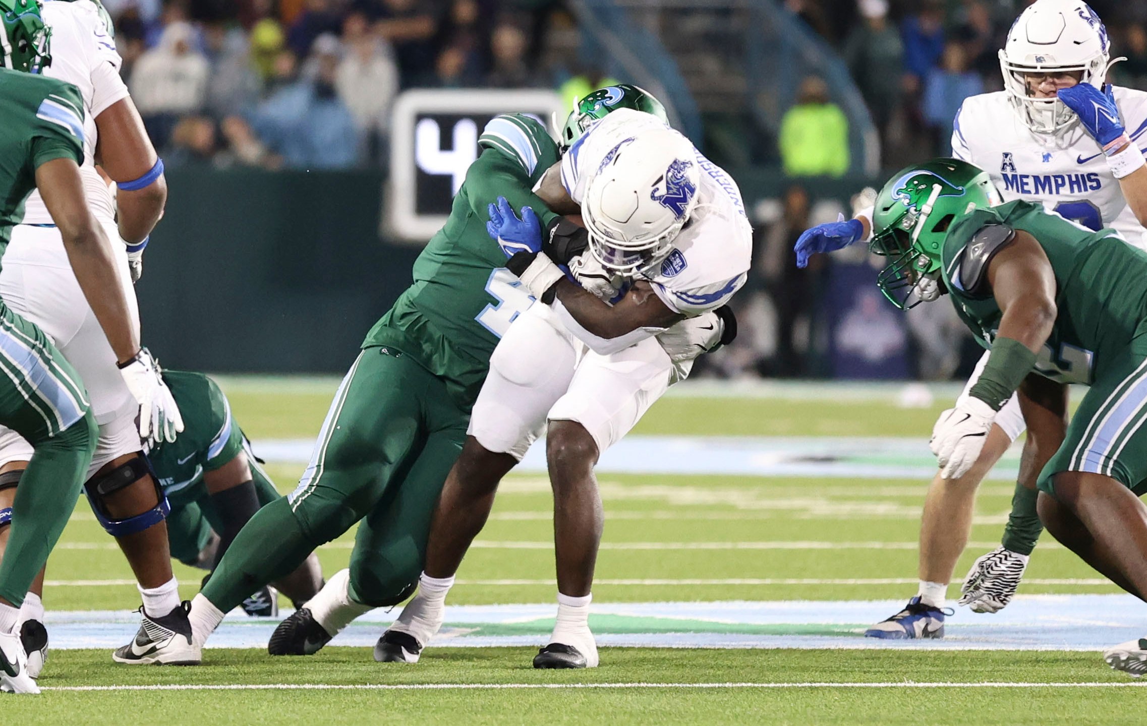 Tulane linebacker Chris Rodgers (4) tackles Memphis wide receiver Roc Taylor, center right, during the first half of an NCAA college football game in New Orleans, Thursday, Nov. 28, 2024. (AP Photo/Peter Forest)