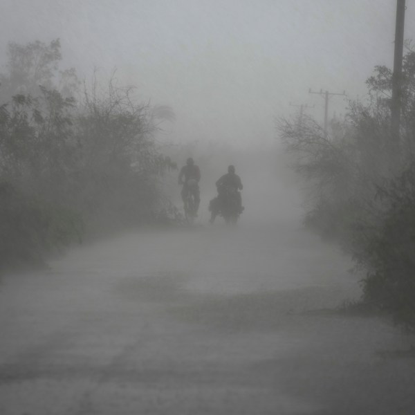 FILE - People travel in the rain after the passage of Hurricane Rafael in Guanimar, Cuba, Nov. 7, 2024. (AP Photo/Ramon Espinosa, File)