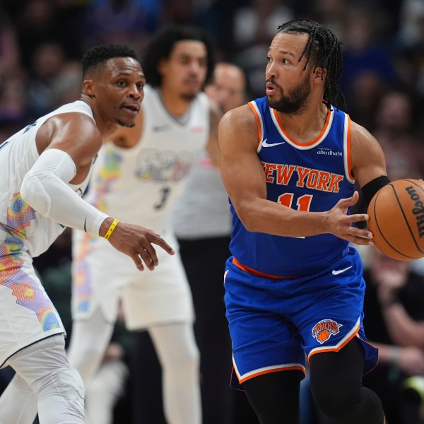 New York Knicks guard Jalen Brunson, right, looks to pass the ball as Denver Nuggets guard Russell Westbrook defends in the second half of an NBA basketball game Monday, Nov. 25, 2024, in Denver. (AP Photo/David Zalubowski)