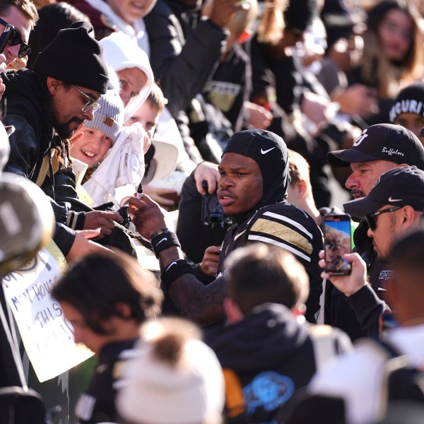 Colorado wide receiver Travis Hunter, center, is surrounded by fans as he heads to the locker room after an NCAA college football game against Oklahoma State, Friday, Nov. 29, 2024, in Boulder, Colo. (AP Photo/David Zalubowski)