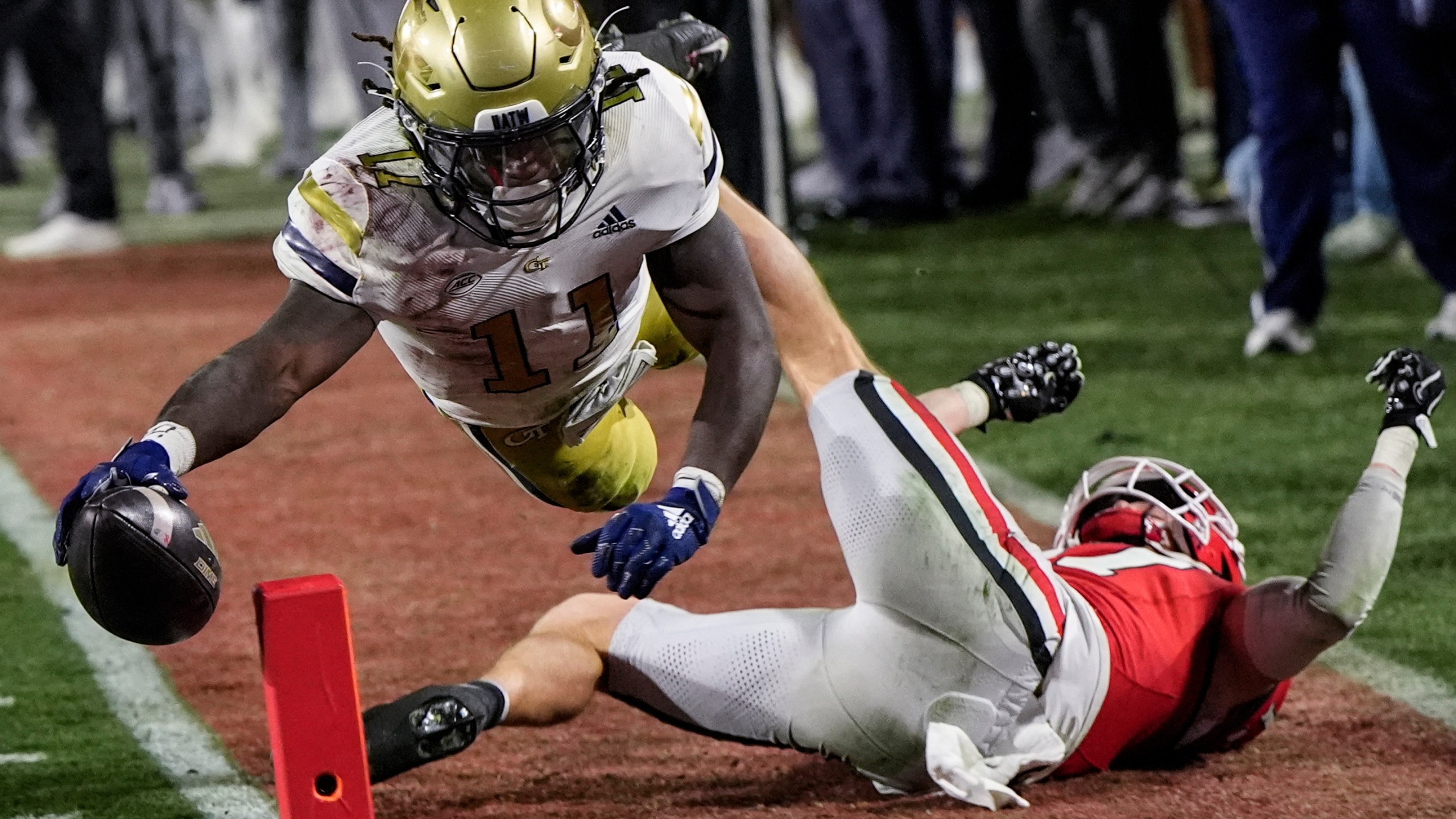 Georgia Tech running back Jamal Haynes (11) leaps into the end zone for a touchdown against Georgia defensive back Dan Jackson (17) during the first half of an NCAA college football game, Friday, Nov. 29, 2024, in Athens, Ga. (AP Photo/Mike Stewart)