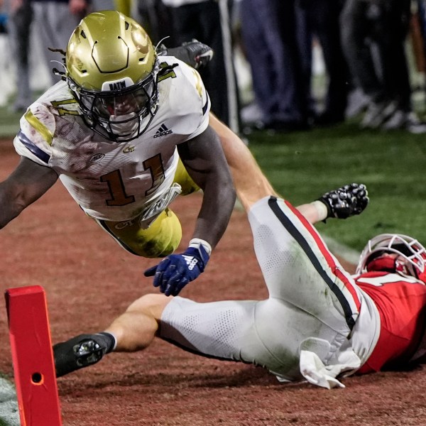 Georgia Tech running back Jamal Haynes (11) leaps into the end zone for a touchdown against Georgia defensive back Dan Jackson (17) during the first half of an NCAA college football game, Friday, Nov. 29, 2024, in Athens, Ga. (AP Photo/Mike Stewart)