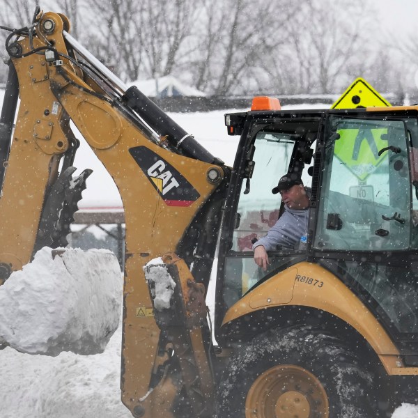 Dwayne Bennett, mayor of Geneva-on-the-Lake, drives a heavy equipment to clear snow as more snow falls Monday, Dec. 2, 2024, in Geneva-on-the-Lake, Ohio. (AP Photo/Sue Ogrocki)