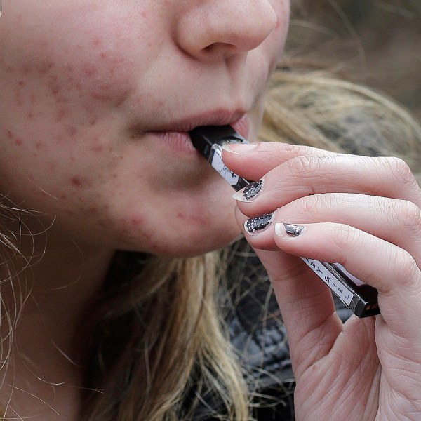 FILE - A high school student uses a vaping device near a school campus in Cambridge, Mass., April 11, 2018. (AP Photo/Steven Senne, File)