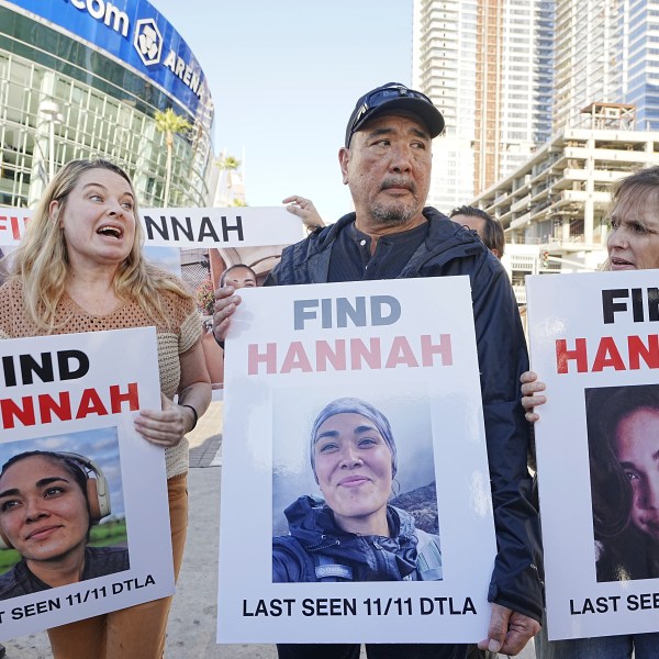 Ryan Kobayashi, center, holds a picture of his missing daughter Hannah Kobayashi outside Crypto.com Arena, Thursday, Nov. 21, 2024 in Los Angeles. (AP Photo/Damian Dovarganes)