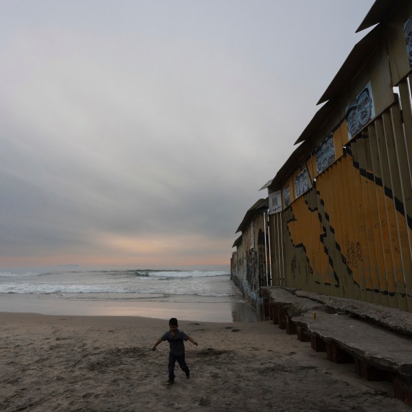 A boy walks near where a border wall separating the United States from Mexico reaches the Pacific Ocean, Tuesday, Nov. 26, 2024, in Tijuana, Mexico. (AP Photo/Gregory Bull)