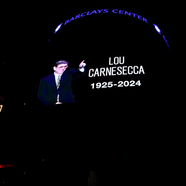 Fans pause for a moment of silence in memory of former St. John's men's basketball coach Lou Carnesecca before an NBA basketball game between the Orlando Magic and the Brooklyn Nets, Sunday, Dec. 1, 2024, in New York. (AP Photo/Noah K. Murray)