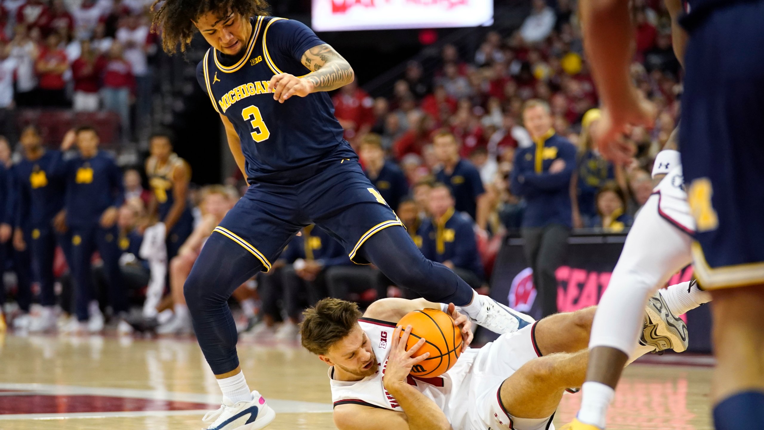 Wisconsin forward Carter Gilmore (7) dives for a loose ball against Michigan guard Tre Donaldson (3) during the first half of an NCAA college basketball game Tuesday, Dec. 3, 2024, in Madison, Wis. (AP Photo/Kayla Wolf)