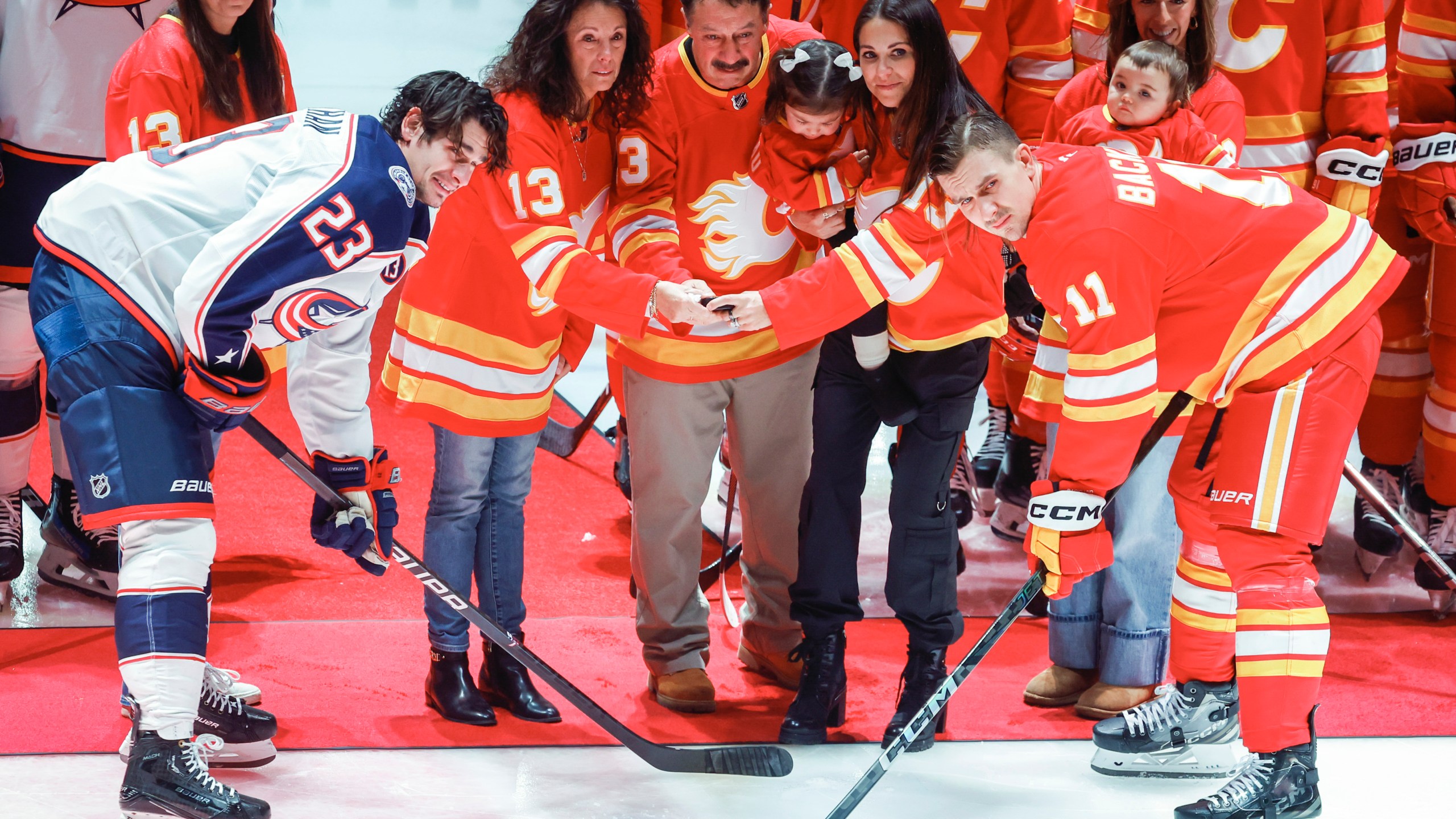 Columbus Blue Jackets' Sean Monahan, left, and Calgary Flames' Mikael Backlund join the family of Johnny Gaudreau at centre ice prior to first period NHL hockey action in Calgary on Tuesday, Dec. 3, 2024.THE CANADIAN PRESS/Jeff McIntosh/The Canadian Press via AP)